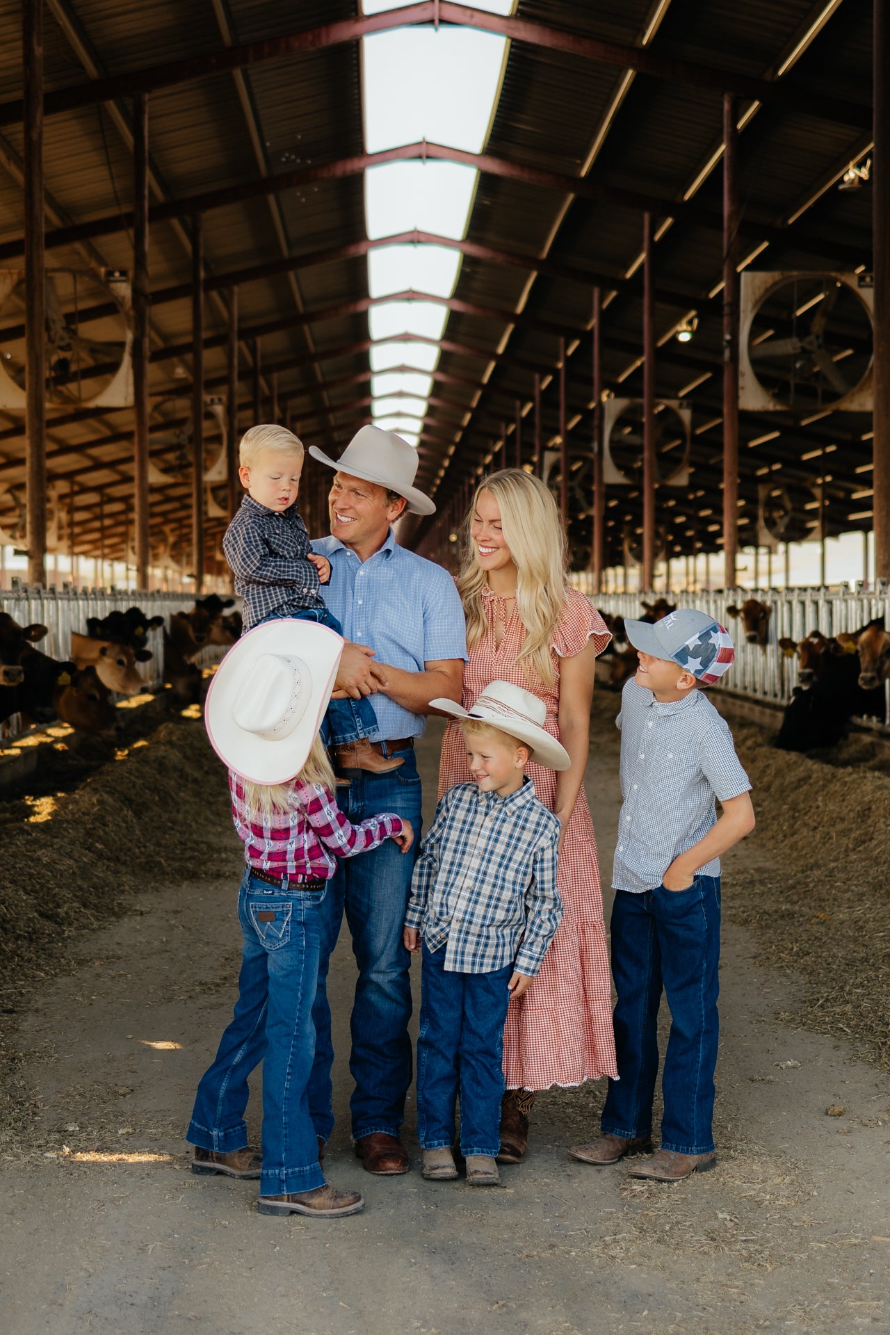 Group picture of Austin Allred and family near cows eating