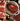 Raw steaks on a cutting board with seasonings and ingredients on a dark surface